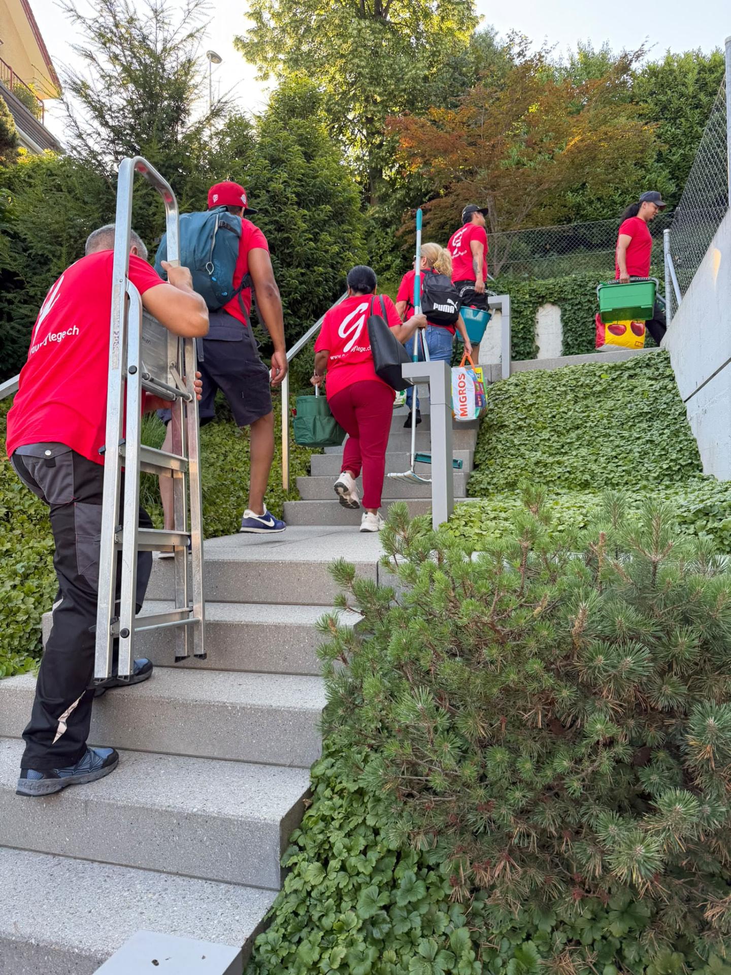 G-Raumpflege-Team mit Reinigungsgeräten auf einer Treppe